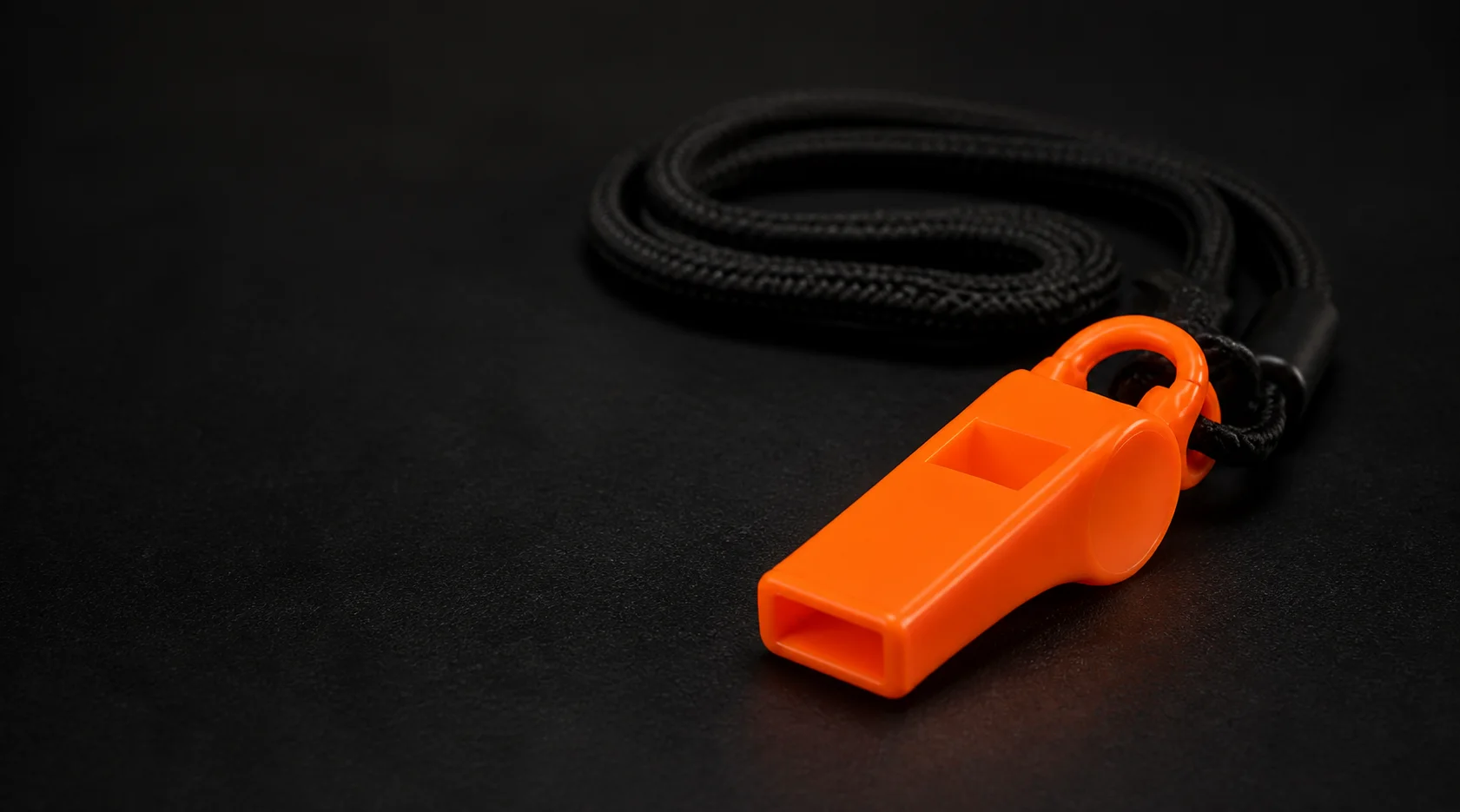 Primer plano del silbato naranja de emergencia con cordón negro